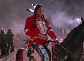 Movie still from “She Wore a Yellow Ribbon” (1949), directed by John Ford – A man sitting on top of a horse in front of a forest; Medium shot, Low angle