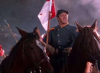 Movie still from “She Wore a Yellow Ribbon” (1949), directed by John Ford – A man in uniform riding on the back of a brown horse; Medium shot, Low angle
