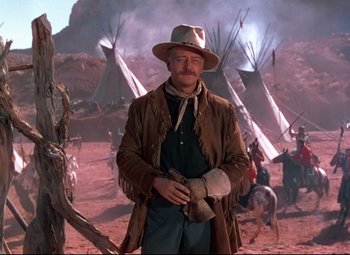 Movie still from “She Wore a Yellow Ribbon” (1949), directed by John Ford – A man in a cowboy hat standing in front of teepees; Medium shot, Over the shoulder angle