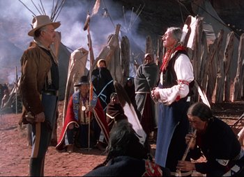 Movie still from “She Wore a Yellow Ribbon” (1949), directed by John Ford – A group of people standing next to each other on a dirt ground; Wide shot, Over the shoulder angle