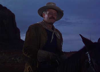 Movie still from “She Wore a Yellow Ribbon” (1949), directed by John Ford – A man wearing a cowboy hat standing next to a horse; Medium shot, Low angle