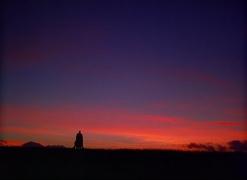 Movie still from “She Wore a Yellow Ribbon” (1949), directed by John Ford – A man sitting on a bench in the middle of a field at sunset; Extreme Wide shot, Low angle