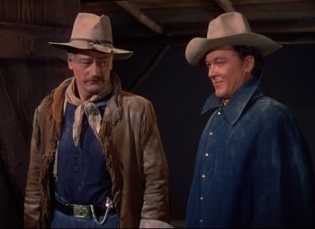 Movie still from “She Wore a Yellow Ribbon” (1949), directed by John Ford – Two men in cowboy hats and jackets standing next to each other; Medium shot, Over the shoulder angle