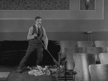 Movie still from “Sherlock Jr.” (1924), directed by Buster Keaton – An old man is sweeping the floor of an auditorium; Wide shot, High angle