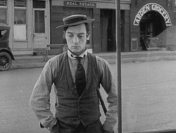 Movie still from “Sherlock Jr.” (1924), directed by Buster Keaton – A black and white photo of a man wearing a hat; Medium shot, Low angle