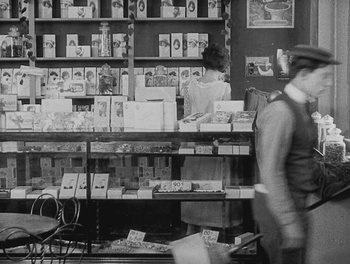 Movie still from “Sherlock Jr.” (1924), directed by Buster Keaton – A man is standing in front of a book case; Wide shot, High angle