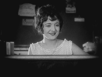 Movie still from “Sherlock Jr.” (1924), directed by Buster Keaton – An old black and white photo of a woman smiling; Close Up shot, Low angle