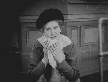 Movie still from “Sherlock Jr.” (1924), directed by Buster Keaton – An older woman holding a napkin in front of her face; Medium shot, Low angle