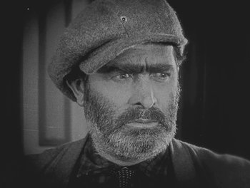 Movie still from “Sherlock Jr.” (1924), directed by Buster Keaton – An older man with a beard wearing a hat; Close Up shot, High angle