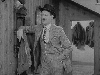 Movie still from “Sherlock Jr.” (1924), directed by Buster Keaton – An old photo of a man in a suit and a hat; Medium shot, Low angle