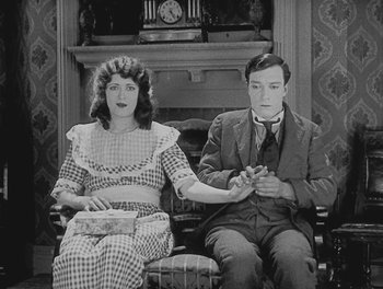 Movie still from “Sherlock Jr.” (1924), directed by Buster Keaton – A man and a woman sitting in a chair; Medium shot, High angle
