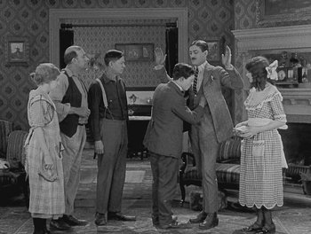 Movie still from “Sherlock Jr.” (1924), directed by Buster Keaton – A group of people standing in a living room; Wide shot, High angle