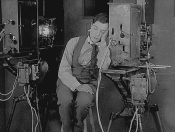 Movie still from “Sherlock Jr.” (1924), directed by Buster Keaton – A man sitting in front of a computer monitor; Medium shot, High angle