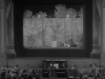 Movie still from “Sherlock Jr.” (1924), directed by Buster Keaton – An audience watching a performance on a stage; Extreme Wide shot, High angle