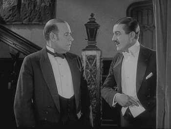 Movie still from “Sherlock Jr.” (1924), directed by Buster Keaton – Two men in tuxedos are standing next to each other; Medium shot, Over the shoulder angle