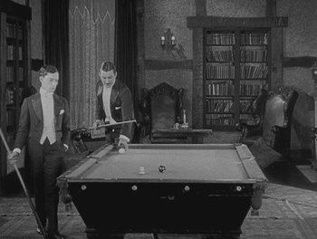 Movie still from “Sherlock Jr.” (1924), directed by Buster Keaton – Three men playing a game of billiards in an old - fashioned living room; Wide shot, High angle