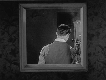 Movie still from “Sherlock Jr.” (1924), directed by Buster Keaton – A black and white photo of a man looking in a mirror; Medium shot, High angle