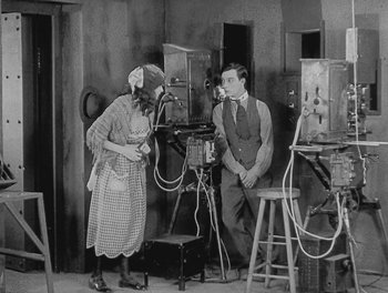 Movie still from “Sherlock Jr.” (1924), directed by Buster Keaton – An old photo of a man and a woman in a room; Medium shot, High angle