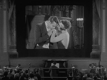 Movie still from “Sherlock Jr.” (1924), directed by Buster Keaton – An old photo of a man and a woman on a screen; Wide shot, High angle