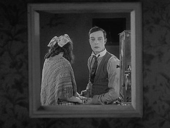 Movie still from “Sherlock Jr.” (1924), directed by Buster Keaton – A man and a woman are looking at each other in a mirror; Medium shot, High angle