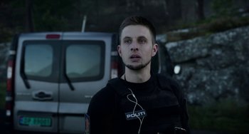 Movie still from “22 July” (2018), directed by Paul Greengrass – A man in a police uniform with headphones on; Close Up shot, Low angle