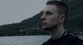 Movie still from “22 July” (2018), directed by Paul Greengrass – A person near a body of water; Close Up shot, Low angle