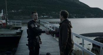 Movie still from “22 July” (2018), directed by Paul Greengrass – Two men shake hands on a dock by the water; Medium shot, Over the shoulder angle
