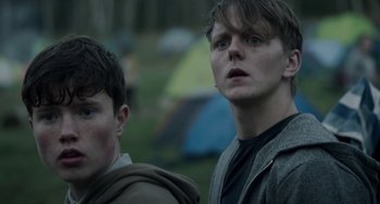 Movie still from “22 July” (2018), directed by Paul Greengrass – Two young men standing next to each other in front of some tents; Close Up shot, Over the shoulder angle