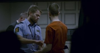 Movie still from “22 July” (2018), directed by Paul Greengrass – A police officer is talking to a man in a red shirt; Medium shot, Over the shoulder angle