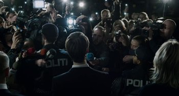 Movie still from “22 July” (2018), directed by Paul Greengrass – A crowd of people gathered around a man in a black suit; Wide shot, Over the shoulder angle