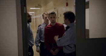 Movie still from “22 July” (2018), directed by Paul Greengrass – A group of men standing next to each other in a hallway; Medium shot, Over the shoulder angle