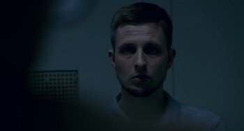 Movie still from “22 July” (2018), directed by Paul Greengrass – A person in a dark room; Close Up shot, Low angle