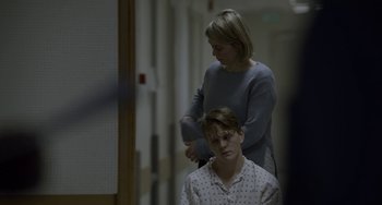 Movie still from “22 July” (2018), directed by Paul Greengrass – A woman combing the hair of a young man; Medium shot, Over the shoulder angle