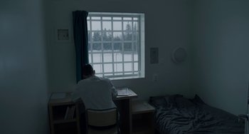 Movie still from “22 July” (2018), directed by Paul Greengrass – A man sitting at a desk in front of a window; Wide shot, High angle