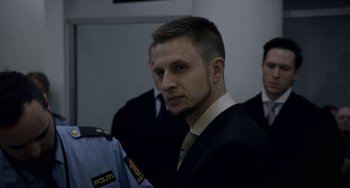 Movie still from “22 July” (2018), directed by Paul Greengrass – A person wearing a suit and tie; Close Up shot, Over the shoulder angle