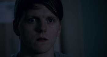 Movie still from “22 July” (2018), directed by Paul Greengrass – A young man stares into the camera in a dimly - lit room; Close Up shot, Over the shoulder angle