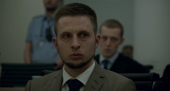 Movie still from “22 July” (2018), directed by Paul Greengrass – A person wearing a suit and tie; Close Up shot, Over the shoulder angle