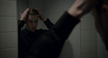 Movie still from “22 July” (2018), directed by Paul Greengrass – A man in a black shirt is in the mirror; Close Up shot, Over the shoulder angle