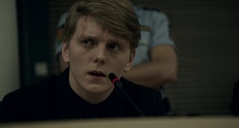 Movie still from “22 July” (2018), directed by Paul Greengrass – A young man with a black shirt is holding a microphone; Close Up shot, Over the shoulder angle