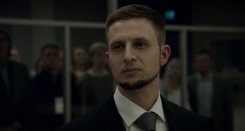 Movie still from “22 July” (2018), directed by Paul Greengrass – A man in a black suit and a gray tie; Close Up shot, Low angle