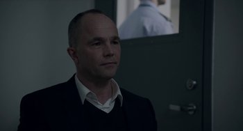 Movie still from “22 July” (2018), directed by Paul Greengrass – A man standing in front of a wall with a picture of a cop; Close Up shot, Over the shoulder angle