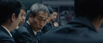 Movie still from “Shin Godzilla” (2016), directed by Shinji Higuchi – A group of men sitting next to each other on a train; Close Up shot, Over the shoulder angle