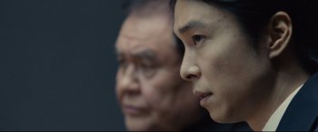 Movie still from “Shin Godzilla” (2016), directed by Shinji Higuchi – A man and a woman looking at the camera; Close Up shot, Over the shoulder angle
