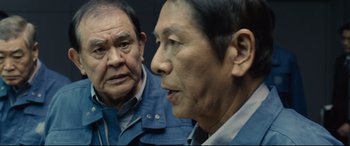 Movie still from “Shin Godzilla” (2016), directed by Shinji Higuchi – Two older asian men standing next to each other; Close Up shot, Over the shoulder angle