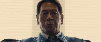 Movie still from “Shin Godzilla” (2016), directed by Shinji Higuchi – A person wearing a blue shirt; Close Up shot, Low angle