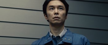 Movie still from “Shin Godzilla” (2016), directed by Shinji Higuchi – A person wearing a blue jacket; Close Up shot, Low angle
