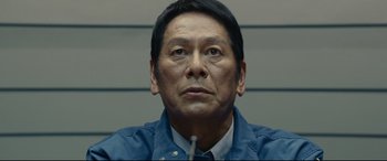 Movie still from “Shin Godzilla” (2016), directed by Shinji Higuchi – A person sitting at a table; Close Up shot, Low angle