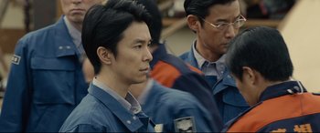 Movie still from “Shin Godzilla” (2016), directed by Shinji Higuchi – Two men in blue work clothes are looking at something; Close Up shot, Over the shoulder angle