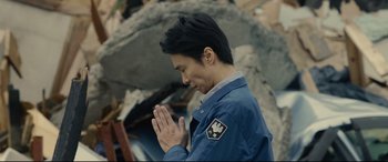 Movie still from “Shin Godzilla” (2016), directed by Shinji Higuchi – A man is praying in front of a pile of rubble; Close Up shot, Low angle