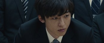 Movie still from “Shin Godzilla” (2016), directed by Shinji Higuchi – A man in a suit and tie looking to his left; Extreme Close Up shot, Low angle